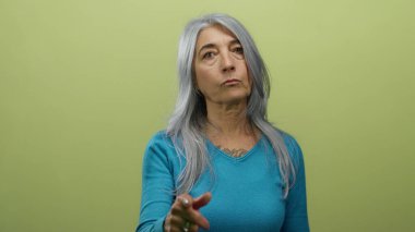 Önünde gri saçlı yaşlı bir kadın, izole edilmiş sarı bir duvara karşı mavi giyiyor..