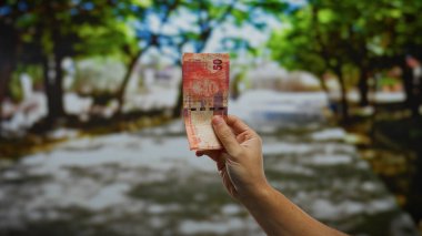 Bir sokak ortamında, Afrika 'nın güneyine ait bir rand ile el ele tutuşmak, canlı bir park atmosferi arasında vurgulanan para birimi işlemleri ile kentsel bir iş ortamı yakalamak..