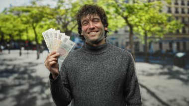 Czech Koruna banknotlarını elinde tutan bir adam güneşli gökyüzünün altında bir şehir ortamında kültür ve finans karışımı sergiliyor..