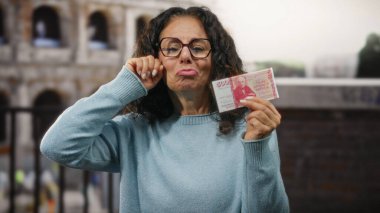 Roma Kolezyumu 'nun yanındaki orta yaşlı kadın elinde İzlanda Krona banknotları ve ağlamaklı bir jest tutarak İtalya' daki seyahat masraflarıyla ilgili ekonomik hayal kırıklığı yaratıyor..