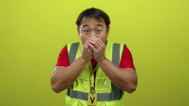 Yelek giyen genç adam sarı arka planda el ele tutuşurken şaşırdı.