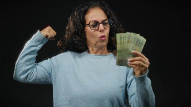 Arjantinli pezoları tutan kadın siyah arka planda güç ve finansal başarı sergiliyor..