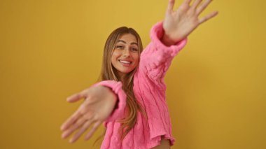 İzole edilmiş sarı arka planda gülümseyen bir kadın pembe kazaklı çekici bir kadın güzel bir poz neşeli bir ruh hali ve zarafeti vurguluyor..