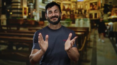 Sakallı İspanyol bir adam güzel aydınlatılmış bir Katolik kilisesinde el çırpıyor, sıcaklığı ve kültürel zenginliği ince detaylarıyla aktarıyor..