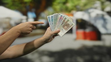 Adam, kalabalık bir şehir caddesinde, Polonya 'daki açık hava mali işlemlerinin özünü yakalayarak elde tutulan Polonya zloti banknotlarını işaret ediyor..