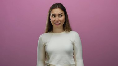 İzole edilmiş pembe arka plan duvarına karşı farklı duygular ifade eden bir kadın bir dizi karede yer alan kafa karışıklığı ve hayal kırıklığını içeren bir dizi yüz ifadesi sergiliyor..