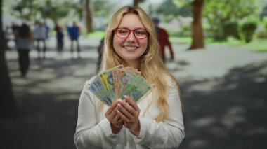 Açık havada gülümseyen bir kadın, elinde Romen leu banknotlarıyla güneşli bir caddede bulanık şehir sakinlerinin arasında bir neşe ve zenginlik anı yakalıyor..
