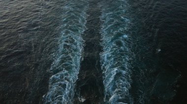 Okyanus dalgaları, alacakaranlık gökyüzü altında belirgin desenler oluşturur hareket halindeki derin mavi suyu yakalar ve havadan çekilen denizin doğal güzelliğini vurgular..