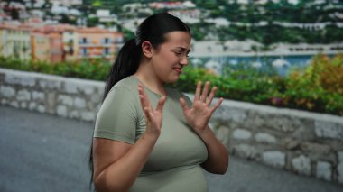 Kıvrımlı vücutlu genç bir kadın deniz kenarındaki bir gezinti alanında isteksizliğini dile getiriyor. Manzaralı bir okyanus manzarasına karşı duygusal bir jest sergiliyor. Reddedilme hissi veriyor..