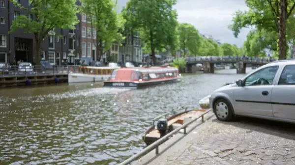 Güneşli bir gökyüzünün altında ikonik mimari sergilenen Amfitik su yolu boyunca bulanık tekne ve araba manzaralı kanal manzarası.