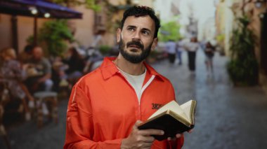 Hapishane tulumlu sakallı bir adam caddenin ortasında İncil 'i tutuyor. Gündüz vakti şehrin arka planında düşünceli bir ifadeyi yansıtıyor..