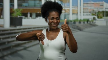 Şehir caddesinde gün ışığında beyaz kolsuz bluz giyerek karışık duygular ifade eden bir kadın..