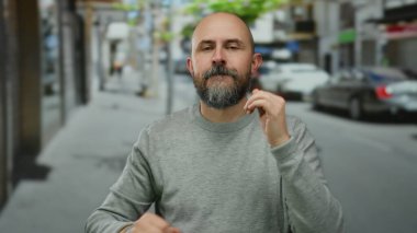 Sakallı kel adam hareketli bir şehir caddesinde enerjik bir şekilde dans ediyor, canlı açık hava atmosferini ve dinamik hareketleri yakalıyor..