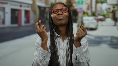 Açık şehir ortamında elinde kripto para tutan kadın, umut ve belirsizlik ifadeleri sergiliyor, şehir yolu arkaplanı ve gözlük takıyor.