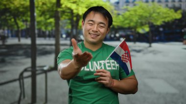 Kentsel caddede elinde Hırvat bayrağı olan Asyalı bir adam ulusal gurur ve gönüllü ruhu açık şehir ortamında sergiliyor..