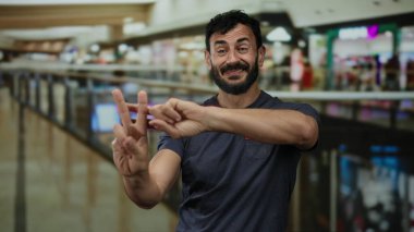 Kalabalık bir alışveriş merkezinde etiketi işaretleyen, İspanyol kökenli, sakallı, sosyal medya eğilimini halka açık bir şehir ortamında yakalayan bir adam..