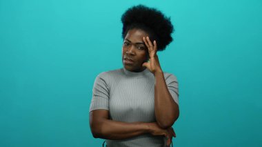 Elleri başlarının üzerinde olan kadın, mavi arka planda stres gösteriyor. Düşünceli bir duruş ve yalnızlığı temsil eden, duygularını ve iç gözlem duygularını aktarıyor..