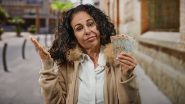 Orta yaşlı, siyah kıvırcık saçlı bir kadın, açık bir şehir sokağında elinde Romen lei banknotları tutuyordu. Düşünceli ve biraz kafası karışmış görünüyordu..