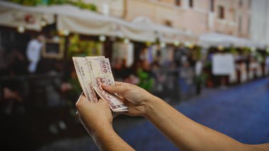 Restoran yakınlarındaki kentsel caddede Tayvan doları sayan bir adam, açık şehir ortamında yatırımları ve ticareti ön plana çıkarıyor..