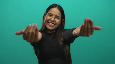 Genç Latin Latin bir model olarak yeşil arka planda kollarını uzatıp izole stüdyoda sarılıyor..