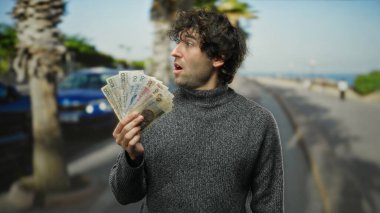 Şehir sokaklarında İspanyol bir adam şaşırtıcı bir şekilde elinde Czech Koruna banknotları tutuyordu. Finansal bir başarı teması sergiliyordu..