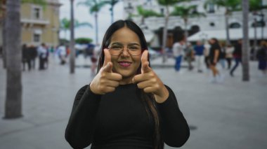 Gülümseyen kadın, hareketli bir caddede insanların güneşli bir günde gezindiği parmaklarıyla işaret ediyor..