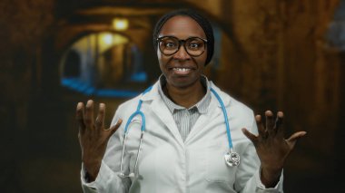 Şehir ortamında, steteskop, gözlük ve sakin tavır takınarak güvenle gülümseyen kadın profesyonel, tıbbi varlığın altını çiziyor..