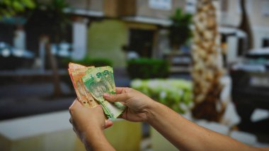 Güney Afrika Rand banknotlarını elinde tutan adam hareketli şehir atmosferinde iş ve finans kavramları için işlek bir sokak vitrininde para gösteriyor..