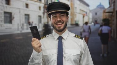 Pilot üniformalı genç adam gururla Avustralya pasaportu taşıyor. Şehir caddesinde, açık havada gülümsüyor..