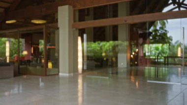 Lobide modern cam tasarımı, yumuşak ışıklandırma ve doğal yeşil manzaralı bulanık lüks tatil köyü var. İçerideki zarafeti, konforu ve sükuneti yansıtıyor..