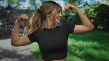 Sarışın genç kadın çıplak kollarını esnetiyor ve güneşli ormanda sabah ışığı altında gülümsüyor; zindelik özgüveni.