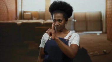 Önlüklü kadın, iş ortamında odak ve yön gösteren bir inşaat alanını işaret ediyor..