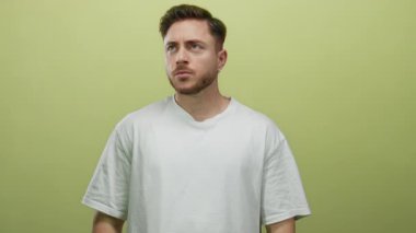 Sakallı genç adam sarı arka planda yalnız. Kulakları kulaklarla kapatıyor. Stres ve hayal kırıklığını ifade ediyor..