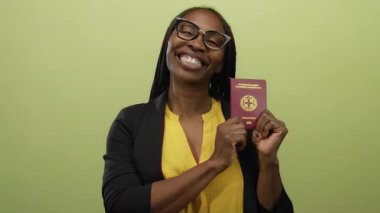 Sarı arka planda gülümseyen Yunan pasaportlu kadın izole edilmiş duvar mutlu seyahat vize belgeleri siyah gözlüklü ceket.