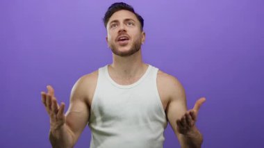 Sakallı genç adam mor arka plana karşı anlamlı jestler yapıyor. Gizli neşeli anlar yaşıyor.