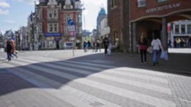 Arka planda bulanık tarihi binalar olan, güneşli bir günde şehir yaşamını ve bokeh etkilerini yakalayan, Avrupa 'nın açık bir caddesinde yürüyen odaksız insanlar..