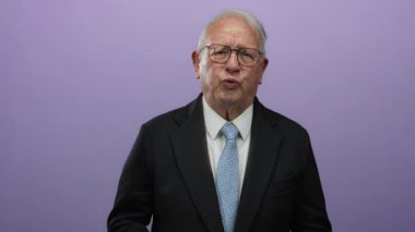 Tecrit edilmiş mor arka planda kıdemli bir adam el üstünde mide rahatsızlığı gösteriyor. Olası acı ya da rahatsızlığı ifade ediyor. Hafif bir sıkıntıyla karşı karşıya..