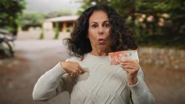 Parktaki kadın Philippine Peso banknotunu elinde tutarken açık hava bahçesinde kendini işaret ederken şaşırdı..