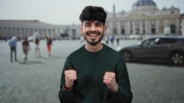 Genç adam, arka planda Aziz Peter Bazilikası ile Vatikan 'da neşeyle gülümsüyor, ikonik bir kent ortamında mutluluk ve turizm taşıyor..
