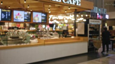 Dijital menü ekranlı bir kafenin bulanık görüntüsü, çözülmüş ışıklarla modern bir kahve dükkanı ortamı sergiliyor, rahat bir ortamda bokeh etkisi yaratıyor..