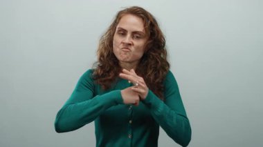 Öfkesini ifade eden bir kadın, beyaz arka plana karşı agresif bir tavırla hareket ediyor kıvırcık saçlı yeşil bir kazak giyiyor ve kafkas görünümlü izole bir ortamda hayal kırıklığını canlı bir şekilde tasvir ediyor.