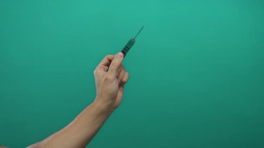 Yeşil izole arka planda maymuncuk tutan adam, detay, beceri ve konsantrasyon vurgulanıyor.