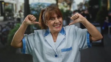 Üniformalı kıdemli İspanyol kadın hareketli bir şehir sokağında dikilirken kendine güvenerek gülümsüyor. Temizlik mesleğiyle gurur duyduğunu söylüyor..