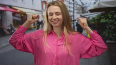 Canlı bir şehir caddesinde, açık havada kutlama yapan, pembe bir gömlek giyen, şehir ortamında neşe ve heyecan saçan, neşeli ve neşeli bir anı yakalayan bir kadın..