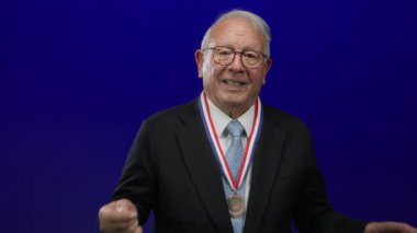 Takım elbiseli kıdemli bir adam, boynundaki madalyayla neşe ve güveni ifade ediyor..