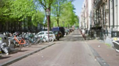 Bisikletler ağaçlarla kaplı yolları olan resimli bir Amsterdam caddesinde dizilmiş, büyüleyici bir Avrupa ortamında kentsel yaşamın bokeh etkisini sergiliyorlar..