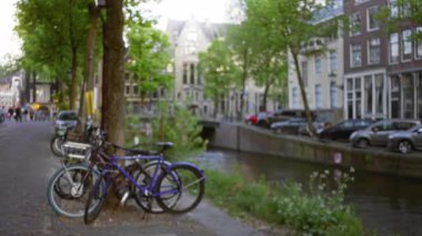 Arka planda bisiklet ve tipik Hollanda mimarisi ile Amsterdam Kanalı 'nın odaksız görünümü, Hollanda kentsel manzarasının özünü yakalıyor.