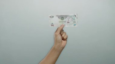 Birleşik Arap Emirlikleri 'nin el ele tutuşması beyaz arka plan gösterimine karşı dirham ve insanların münferit ortamdaki mali hareketleri.