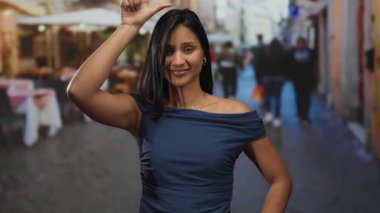 Bir kadın restoran terasında güvenle poz veriyor, şık giyinmiş sokak arkaplanı ile şehir yaşamını gösteriyor..