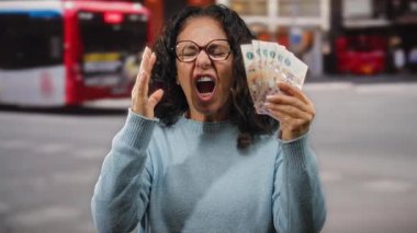 Şehir caddesinde elinde kızgın bir ifadeyle Arjantin pesoları tutan kadın, para ve ekonomik strese karşı açık hava hayal kırıklığını vurguluyor..